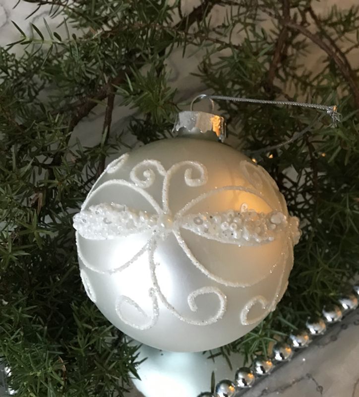 Julekule i matt sølv med hvit ornament.
