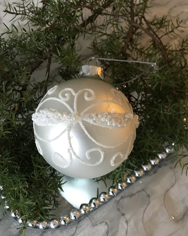 Julekule i matt sølv med hvit ornament.